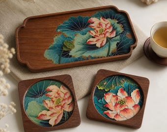 May include: A wooden serving tray and two square coasters with a floral design. The tray and coasters feature a dark wood frame and a colourful illustration of a lotus flower with green leaves and a pink and orange flower.