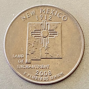 May include: A United States quarter coin featuring the New Mexico state design. The coin displays the words "New Mexico 1912" at the top, and "Land of Enchantment 2008" at the bottom. The coin has a silver color.