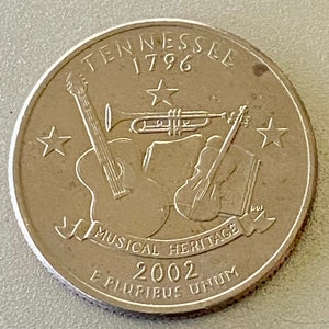 May include: Silver US quarter coin featuring a trumpet, guitar, and violin with the text "Tennessee 1796 Musical Heritage 2002 E Pluribus Unum".