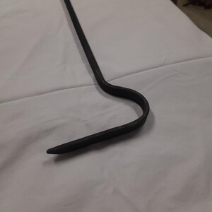 May include: A black metal fireplace poker with a curved hook at the end.
