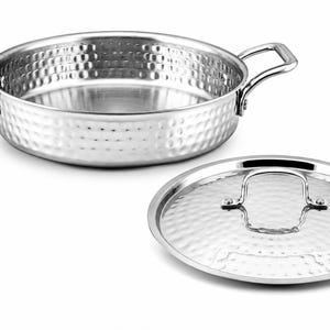 Pode incluir: Panela de cozinha em aço inoxidável com acabamento martelado, duas pegas e uma tampa a condizer. A panela e a tampa são prateadas e têm uma superfície texturizada. A tampa tem uma pega. Utensílios de cozinha.