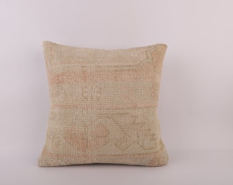 May include: A square, off-white throw pillow with a woven texture. The pillow has a subtle pink and white pattern.