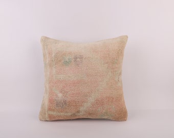 May include: A square cushion with a beige and pink woven fabric. The cushion has a subtle floral pattern.