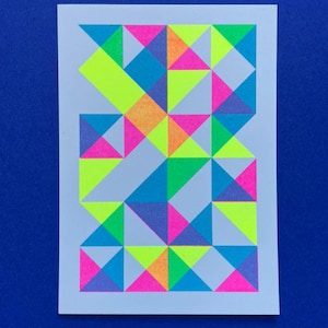 Op de afbeelding: Een geometrisch patroon van driehoeken in verschillende kleuren, waaronder roze, blauw, groen, geel en oranje, op een witte achtergrond.