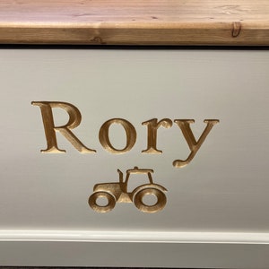 May include: A white wooden toy box with a gold-colored inscription that reads "Rory" and a gold-colored tractor image.