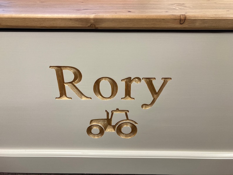 May include: A white wooden toy box with a gold-colored inscription that reads "Rory" and a gold-colored tractor image.