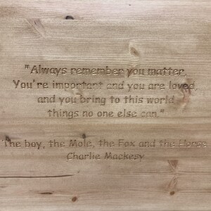 May include: A wooden sign with an inspirational quote engraved in the wood. The quote reads "Always remember you matter, You're important and you are loved, and you bring to this world things no one else can." The sign is attributed to "The boy, the Mole, the Fox and the Horse, Charlie Mackesy."