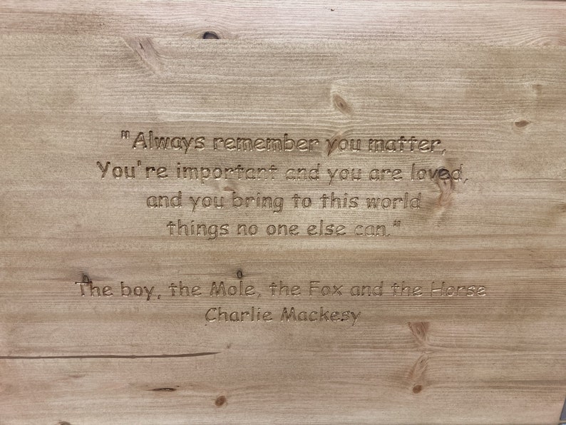 May include: A wooden sign with an inspirational quote engraved in the wood. The quote reads "Always remember you matter, You're important and you are loved, and you bring to this world things no one else can." The sign is attributed to "The boy, the Mole, the Fox and the Horse, Charlie Mackesy."