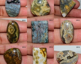 May include: Assortment of ten polished, natural, oval, rectangular, and triangular shaped ocean jasper cabochons in various shades of green, brown, blue, and white with intricate patterns.
