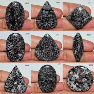 Peut inclure: Dix cabochons de pierres précieuses de différentes formes et tailles. Les pierres sont noires avec des taches blanches et rouges. Les pierres sont disposées en grille.