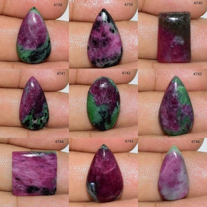 May include: Assortment of 10 green and pink gemstone cabochons in various shapes and sizes. The cabochons are displayed on a hand.