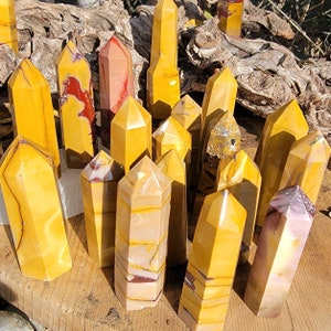 May include: A collection of yellow, red, and brown striped crystal points. The points are arranged in a semi-circle on a wooden surface.