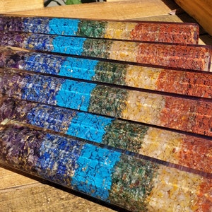 May include: A set of seven chakra healing wands, each with a different color and crystal. The wands are made of clear resin and feature a variety of crystals, including amethyst, clear quartz, citrine, green aventurine, turquoise, lapis lazuli, and red jasper.