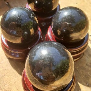 May include: Four black obsidian spheres on wooden stands. The spheres are polished and reflect light.