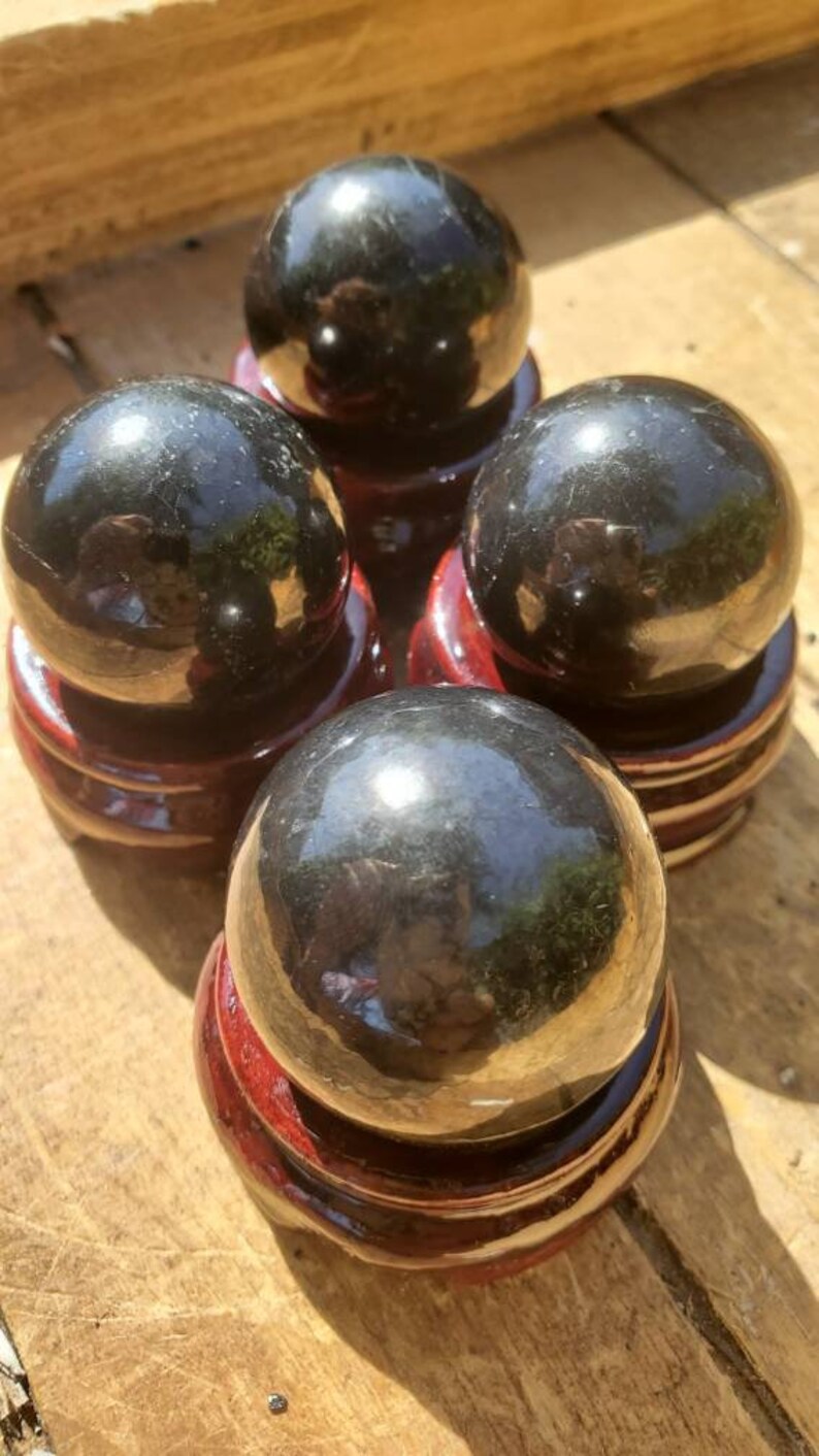 May include: Four black obsidian spheres on wooden stands. The spheres are polished and reflect light.