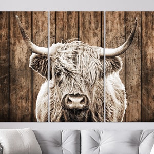 May include: A black and white photograph of a Highland cow with long, shaggy hair, set against a rustic wooden background.