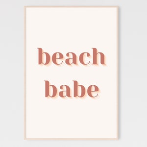 Puede incluir: Un fondo blanco con el texto "beach babe" en un color rosa melocot&oacute;n con un efecto de sombra.