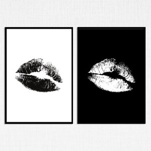 May include: Two framed prints of a black and white image of a lipstick kiss mark. The left print has a white background and the right print has a black background.