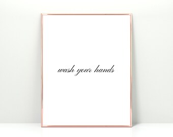 May include: A white framed print with the text "wash your hands" in black cursive writing.