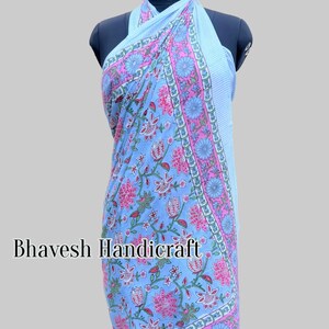 May include: A light blue cotton sarong with a floral print in shades of pink, green, and white. The sarong is tied around a mannequin and has a halter neck style. The text "Bhavesh Handicraft" is visible on the sarong.