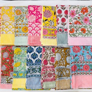 May include: A collection of 12 colourful cotton napkins with floral and geometric patterns. The napkins are arranged in two rows of six, with each napkin having a different design. The napkins are all approximately 45 cm by 45 cm.