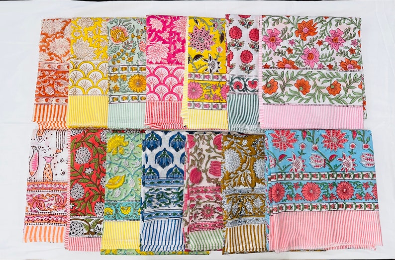 May include: A collection of 12 colourful cotton napkins with floral and geometric patterns. The napkins are arranged in two rows of six, with each napkin having a different design. The napkins are all approximately 45 cm by 45 cm.