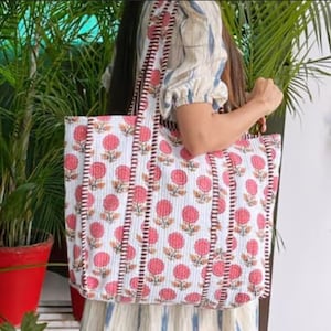 Peut inclure: Un sac cabas blanc avec un imprimé floral rose et une bordure rouge. Le sac a une grande capacité et est parfait pour transporter les essentiels du quotidien.