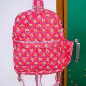 Puede incluir: Una mochila de color rosa y blanco con un peque&ntilde;o bolsillo en el lateral. La mochila tiene un cierre de cord&oacute;n y correas ajustables.