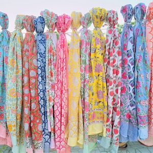 May include: A collection of colourful cotton scarves with floral patterns. The scarves are hanging on a clothesline and are all different colours and designs.