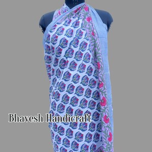 May include: A blue and white cotton sarong with a floral print. The sarong has a pink and white border with a striped pattern. The sarong is draped over a mannequin.