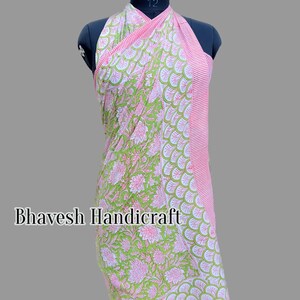 May include: A green and pink cotton sarong with a floral print and a pink and white striped border. The sarong is draped over a mannequin.