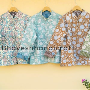 May include: Five quilted jackets with floral patterns in various colours, including white, pink, blue, green, and brown. The jackets are hanging on hangers against a yellow wall. The text "Bhaveshhandicraft" is visible in the centre of the image.