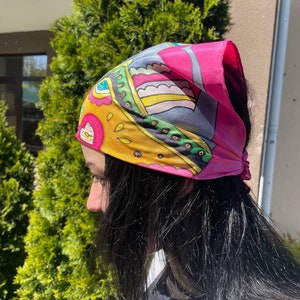 May include: A pink, yellow, green, and blue patterned bandana tied around a person's head.