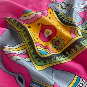 This is a hot pink Indian style small elephant scarf. The scarf is decorated with a gold outline for the fabric. Soft natural silk, edges rolled by hand. Sold in a gift round cardboard box.