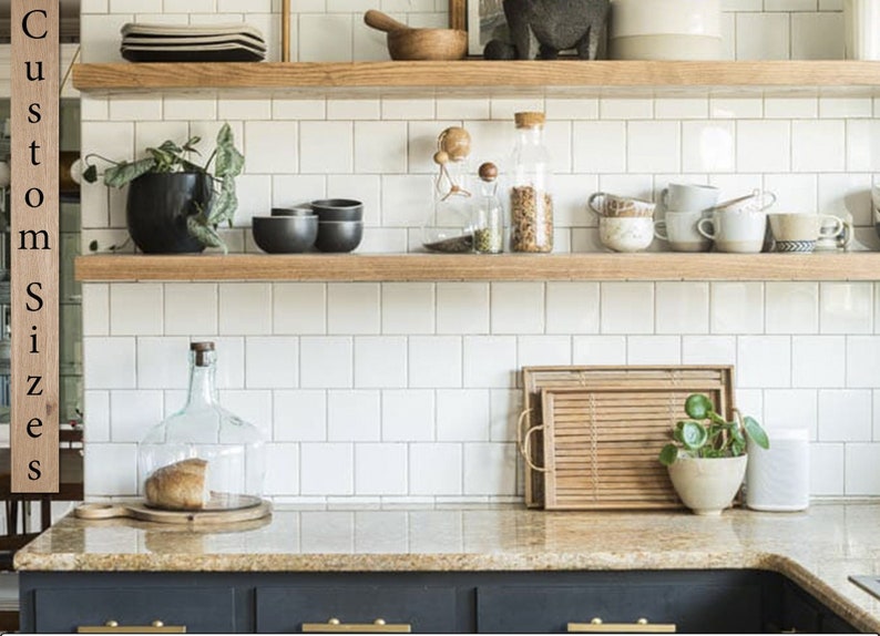 May include: A kitchen scene with wooden shelves displaying various items. There are black bowls, clear glass jars, and white mugs. A glass cloche covers a loaf of bread. A wooden tray and a small potted plant are on the countertop. The text "Custom Sizes" is on the left.