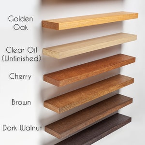 May include: Image showcasing a selection of White Oak wood color choices. The options include Light Brown, Golden Oak, Clear Oil (Unfinished), Cherry, Brown, Dark Walnut, and Ebony. Each color is displayed on a rectangular shelf.