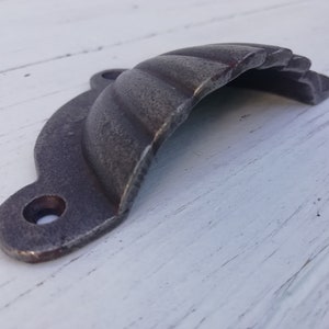 Könnte beinhalten: Ein silberfarbener Metall-Schubladenzug mit einem gewellten Design. Der Zug hat zwei Löcher zur Montage.