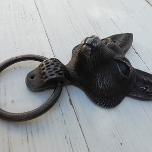 Könnte beinhalten: Ein schwarzer Türklopfer aus Metall in Form eines FuchsKopfes mit einem Ringgriff. Der Fuchs Kopf ist mit Fell detailliert und hat einen realistischen Ausdruck.