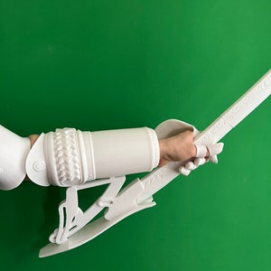 May include: White 3D printed arm guard and sword with intricate details. The arm guard has a braided design and the sword has a decorative handle.