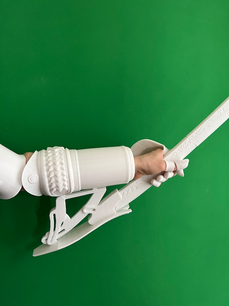 May include: White 3D printed arm guard and sword with intricate details. The arm guard has a braided design and the sword has a decorative handle.