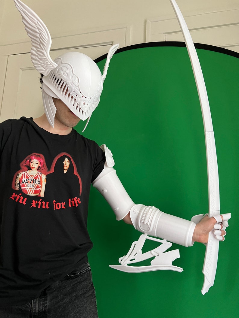 May include: White 3D printed helmet with wings, arm armor, and a sword. The helmet has a detailed design with a face mask. The arm armor is detailed and has a wrist guard. The sword is long and curved.
