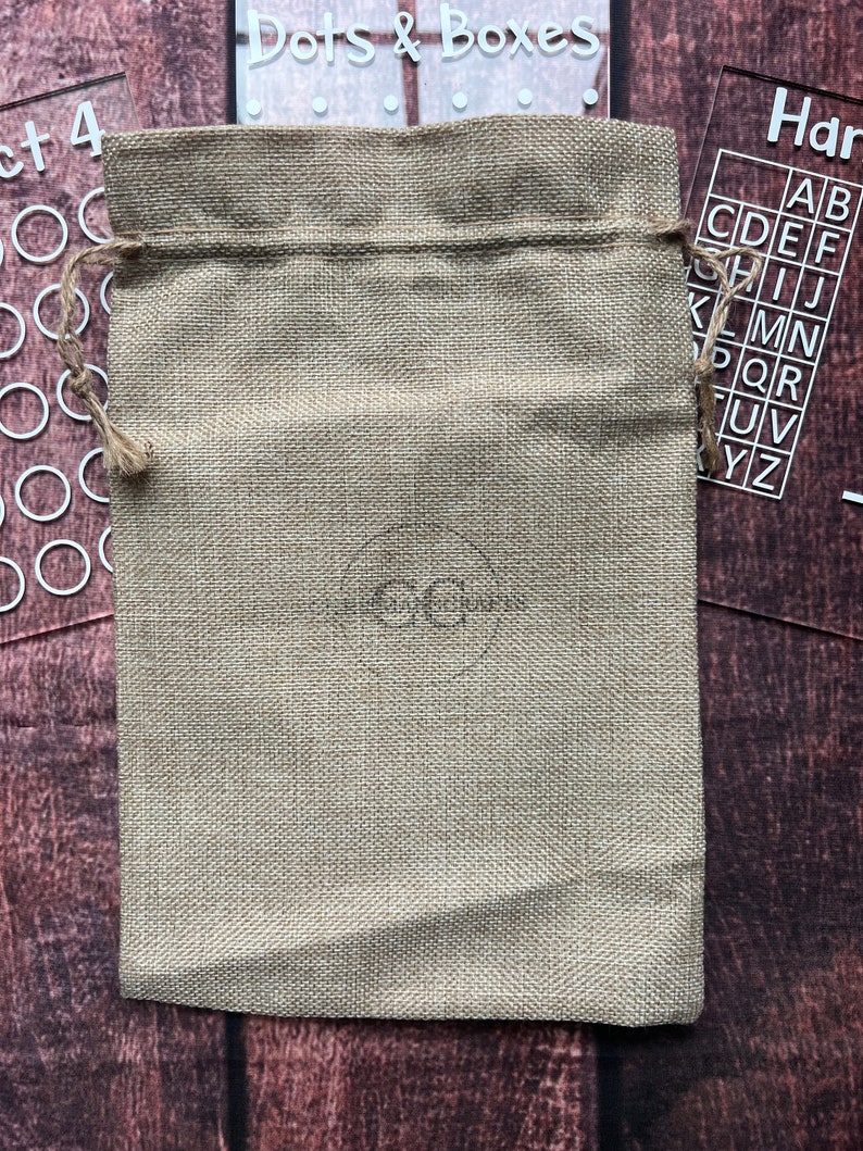 May include: A beige burlap drawstring bag with a brown drawstring. The bag is sitting on a wooden surface.
