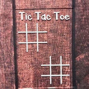 May include: A white sign with the words "Tic Tac Toe" written on it. The sign has two tic-tac-toe grids drawn on it.