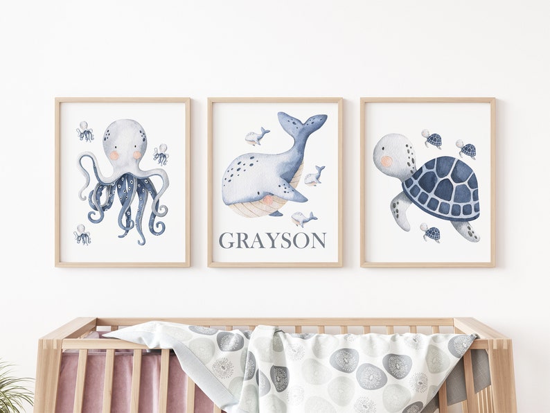 May include: Three watercolor prints featuring a blue octopus, a whale, and a turtle. The whale print has the name Grayson written below it.