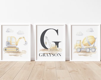May include: Three watercolour prints featuring construction vehicles. The first print shows a yellow excavator with a grey cab. The second print shows a black letter G with a yellow crane and the name Grayson. The third print shows a yellow cement mixer truck with a grey cab.