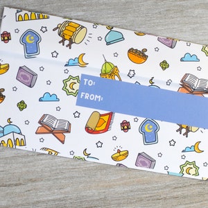 May include: A white envelope with a blue label that says "TO: FROM:". The envelope is decorated with a pattern of Islamic symbols, including stars, crescents, mosques, and prayer rugs.