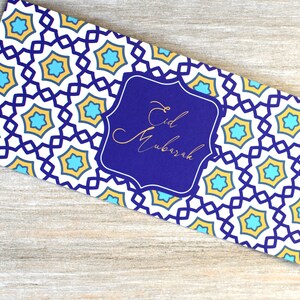 May include: A blue and white card with a gold geometric pattern and the text "Eid Mubarak" in a gold frame.