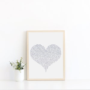 May include: A framed print of a heart shape made of handwritten text. The text is in a dark blue color and is set against a white background. The frame is a light wood color.