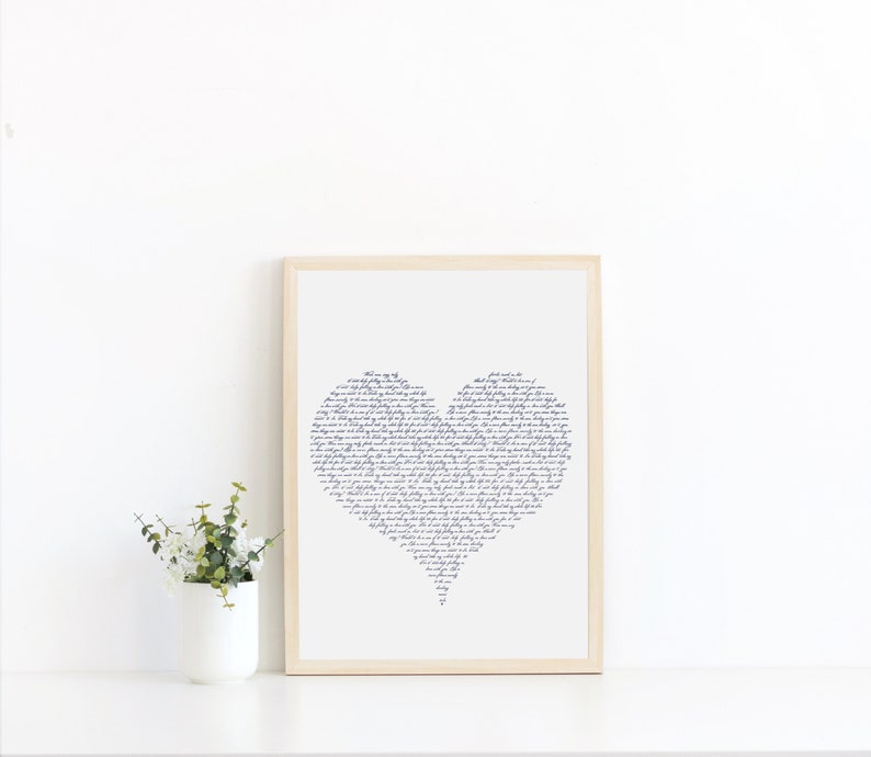 May include: A framed print of a heart shape made of handwritten text. The text is in a dark blue color and is set against a white background. The frame is a light wood color.