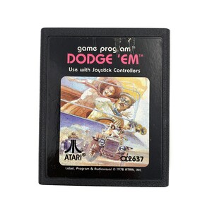 May include: A black Atari game cartridge with a colourful illustration of a car and people on the front. The game title is "DODGE 'EM" and the cartridge number is "CX2637".